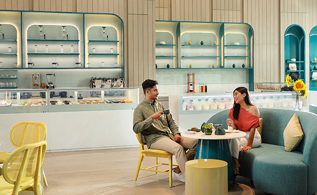 Couple drinking a cup of coffee and eating cake in a comfortable and colourful cafe at Goolali Gelato Bar & Patisserie in Semarang